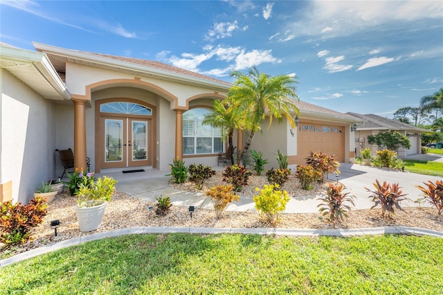 240 White Marsh Ln, Rotonda West, FL 33947 - doorway to property featuring concrete driveway, a garage, stucco siding, and french doors