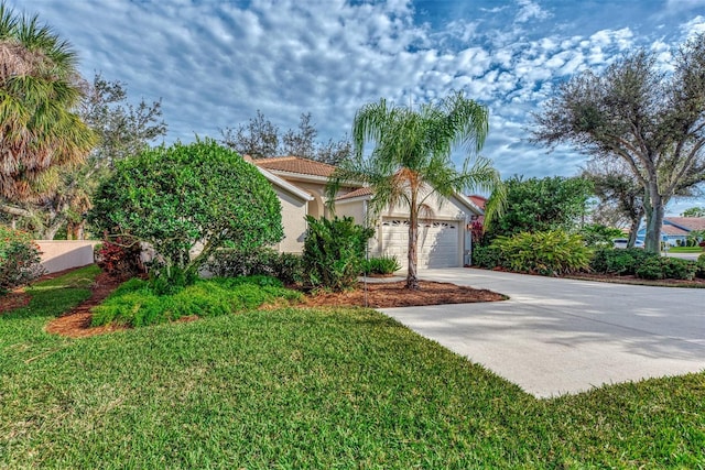 view of front of home with driveway, a tile roof, a front yard, and stucco siding