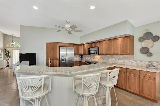 kitchen with ceiling fan, lofted ceiling, tasteful backsplash, stainless steel appliances, and a breakfast bar area