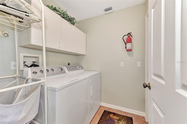 laundry room featuring washing machine and clothes dryer, cabinets, and light tile patterned floors