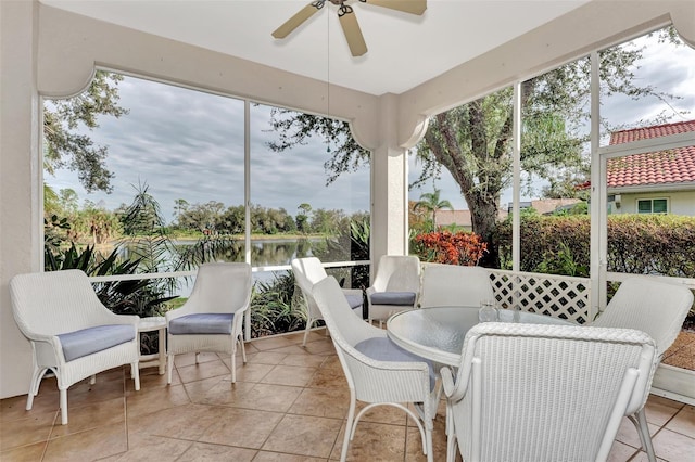 sunroom / solarium with ceiling fan and a water view