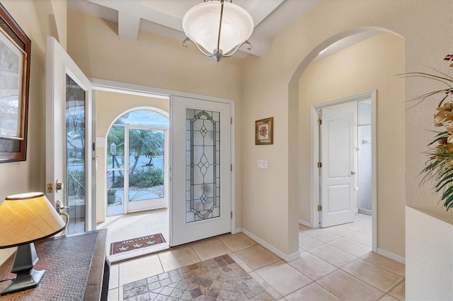 foyer with beamed ceiling and light tile patterned flooring