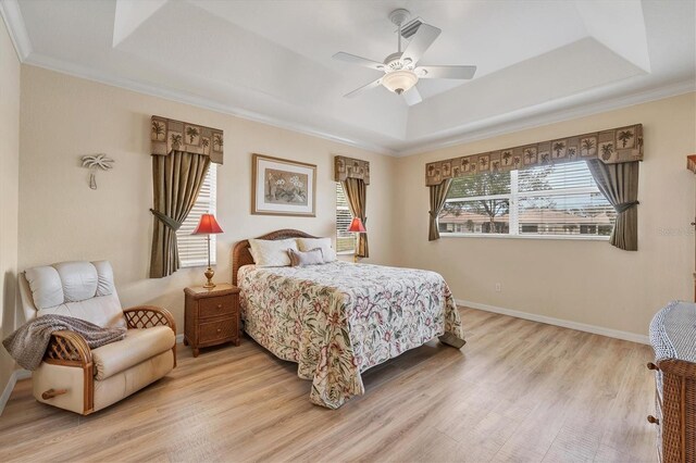 bedroom featuring crown molding, a raised ceiling, light wood-type flooring, and ceiling fan