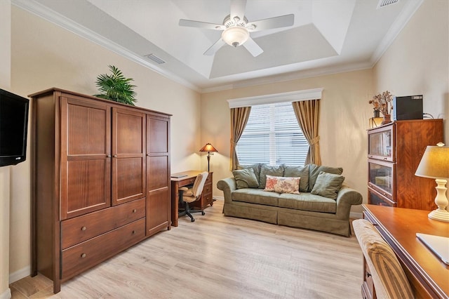 living area with light hardwood / wood-style flooring, ceiling fan, a tray ceiling, and crown molding