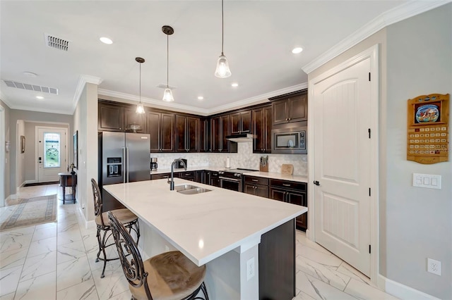 kitchen with pendant lighting, sink, a center island with sink, and appliances with stainless steel finishes