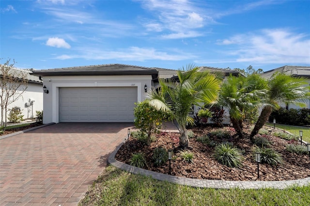 view of front of house with stucco siding, a tile roof, a garage, and decorative driveway