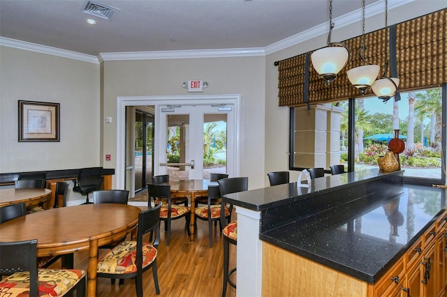 kitchen with hanging light fixtures, ornamental molding, hardwood / wood-style flooring, and french doors