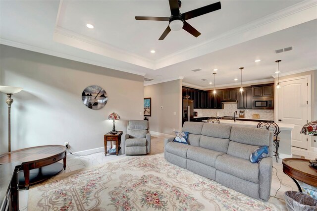 living room with ceiling fan, ornamental molding, and a raised ceiling