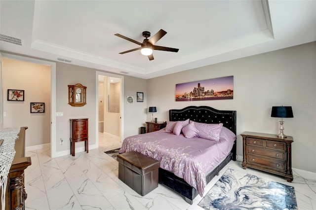 bedroom featuring a tray ceiling, ceiling fan, and ensuite bathroom