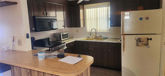 kitchen with decorative backsplash, electric stove, dark brown cabinetry, sink, and white refrigerator