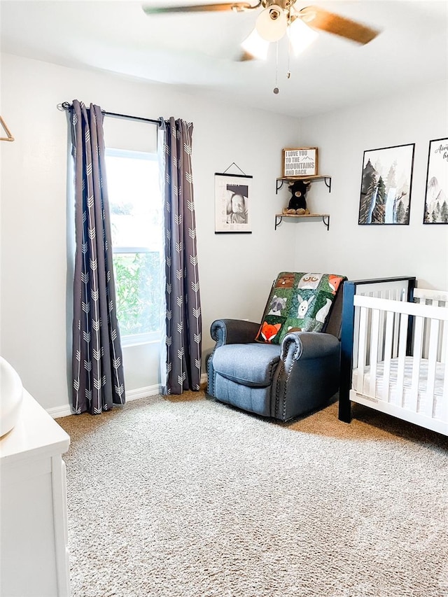 bedroom with ceiling fan, a nursery area, and carpet floors