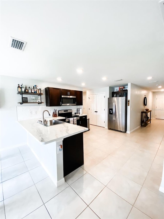 kitchen featuring dark brown cabinetry, sink, stainless steel appliances, kitchen peninsula, and light tile patterned floors