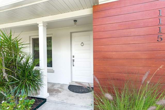 view of exterior entry featuring covered porch