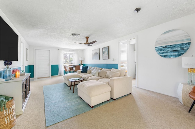 living room with light carpet, a textured ceiling, and ceiling fan