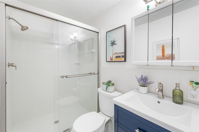 bathroom featuring toilet, vanity, tile walls, a textured ceiling, and an enclosed shower