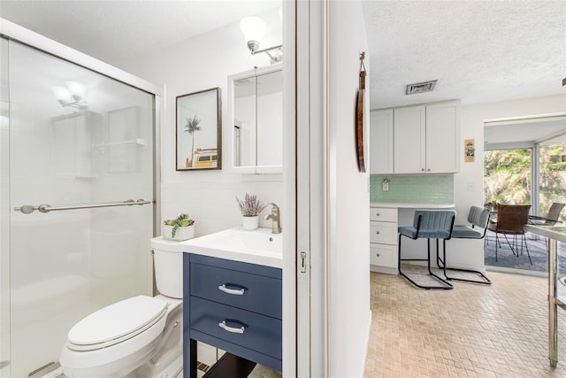 bathroom with backsplash, a textured ceiling, walk in shower, toilet, and vanity