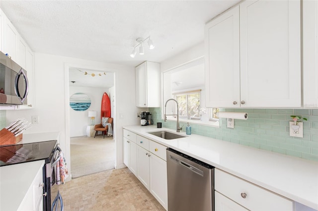 kitchen featuring decorative backsplash, stainless steel appliances, sink, white cabinets, and a textured ceiling