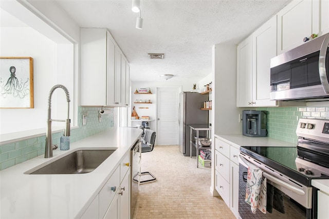 kitchen with appliances with stainless steel finishes, white cabinets, sink, and a textured ceiling