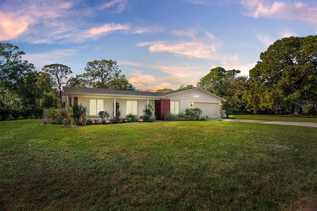 ranch-style house featuring a garage and a lawn