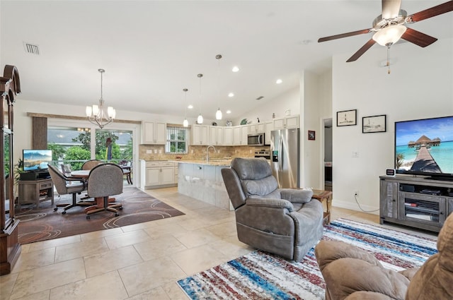 living room featuring ceiling fan with notable chandelier, high vaulted ceiling, sink, and light tile patterned floors