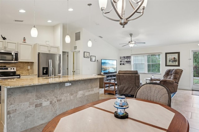 dining area featuring vaulted ceiling, ceiling fan, sink, and light tile patterned floors