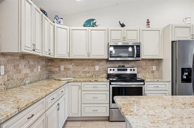 kitchen with light tile patterned flooring, appliances with stainless steel finishes, light stone countertops, and decorative backsplash