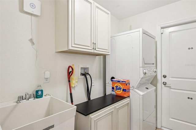 laundry area featuring sink, cabinets, and stacked washing maching and dryer