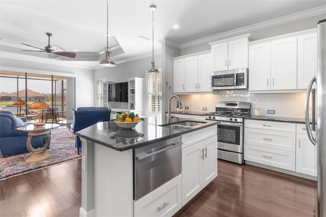 kitchen with sink, white cabinetry, hanging light fixtures, stainless steel appliances, and a kitchen island with sink