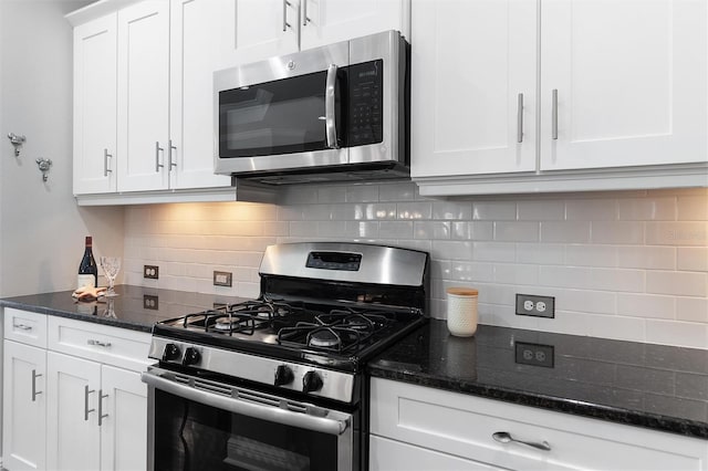 kitchen with backsplash, stainless steel appliances, dark stone counters, and white cabinets