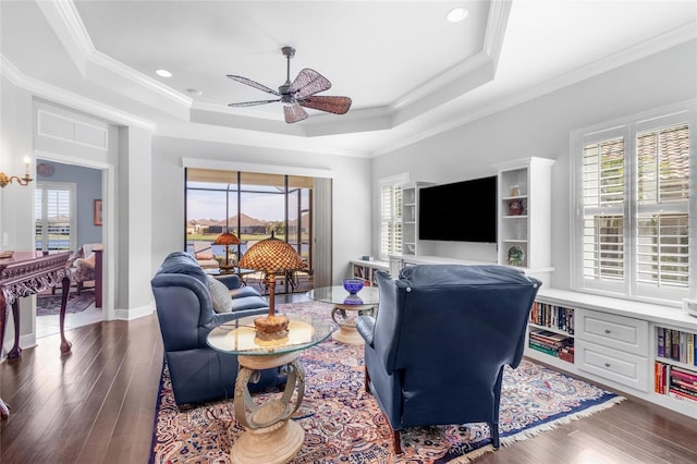 living room featuring a tray ceiling, ornamental molding, and ceiling fan