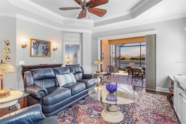 living room with ornamental molding, hardwood / wood-style floors, ceiling fan, and a tray ceiling