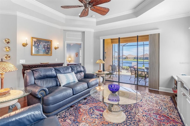 living room featuring a tray ceiling, ornamental molding, ceiling fan, and a water view