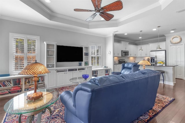 living room featuring a raised ceiling, crown molding, dark hardwood / wood-style floors, and ceiling fan