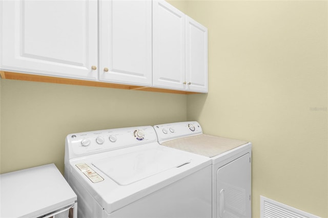 laundry room with washing machine and dryer and cabinets