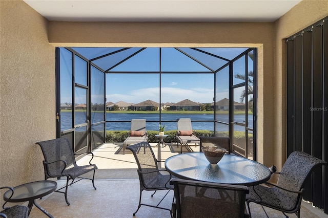 view of patio / terrace featuring a water view and glass enclosure