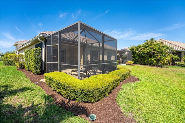 rear view of property with a lanai, a lawn, and a patio