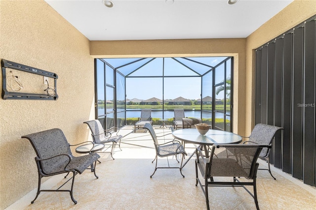 view of patio with glass enclosure and a water view