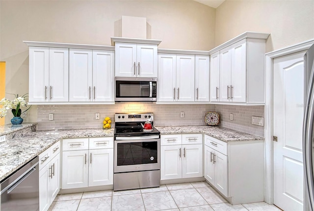 kitchen with backsplash, appliances with stainless steel finishes, light stone counters, and white cabinetry