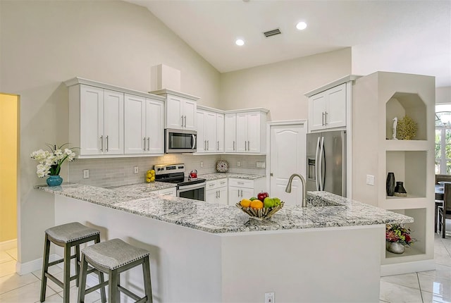 kitchen featuring stainless steel appliances, kitchen peninsula, and white cabinetry