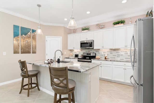 kitchen with an island with sink, hanging light fixtures, sink, white cabinets, and appliances with stainless steel finishes