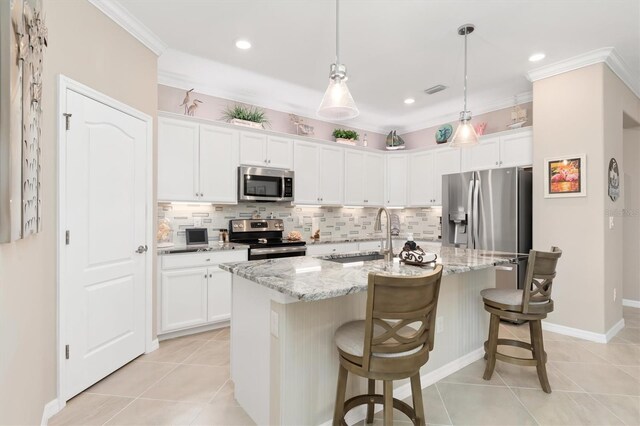 kitchen with appliances with stainless steel finishes, sink, an island with sink, white cabinetry, and pendant lighting