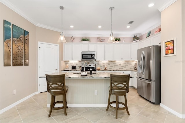 kitchen featuring stainless steel appliances, a center island with sink, crown molding, pendant lighting, and white cabinets