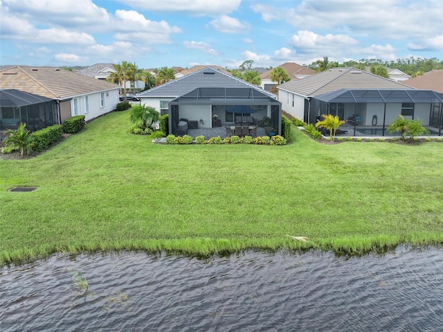 rear view of house with a yard, a water view, and glass enclosure