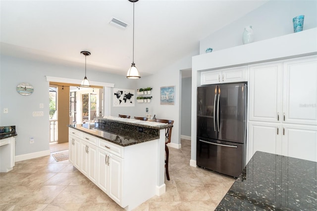 kitchen featuring decorative light fixtures, dark stone countertops, white cabinets, fridge, and a center island