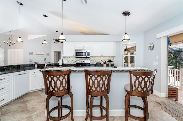 kitchen featuring pendant lighting, stainless steel appliances, a breakfast bar, and white cabinets