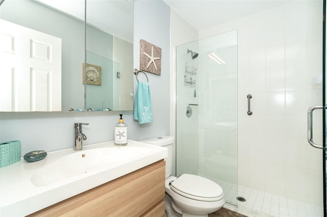 bathroom featuring vanity, a shower with shower door, and toilet