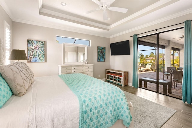 bedroom with ceiling fan, a raised ceiling, hardwood / wood-style flooring, crown molding, and access to exterior