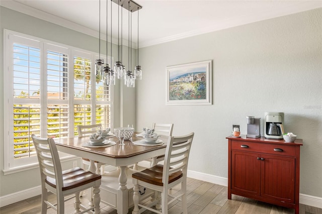 dining room with ornamental molding and light hardwood / wood-style flooring