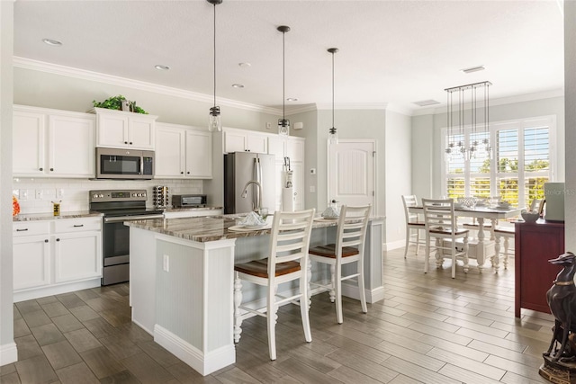 kitchen featuring appliances with stainless steel finishes, stone countertops, a kitchen island with sink, and white cabinetry