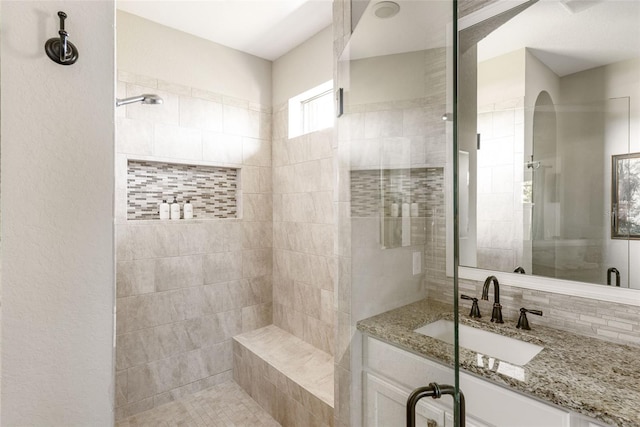 bathroom with decorative backsplash, a shower with door, and vanity